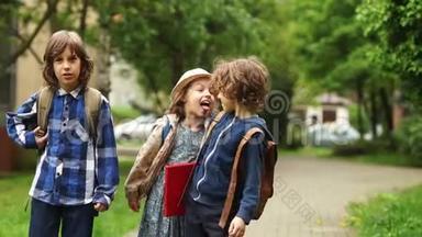 两个男孩和女孩放学后回家。 孩子们胡闹笑，女孩露出舌头。 学校